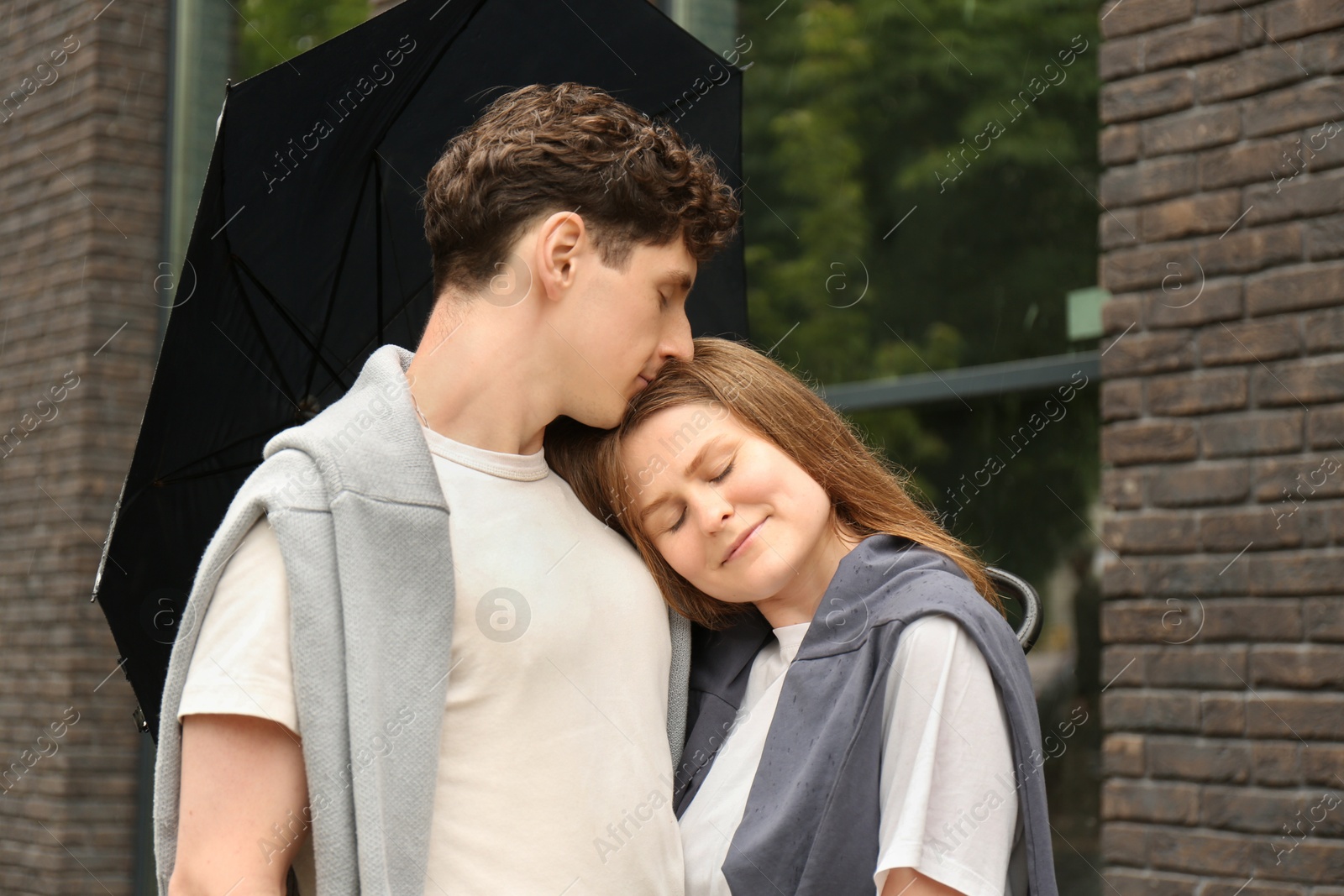 Photo of International dating. Lovely young couple with umbrella spending time together outdoors