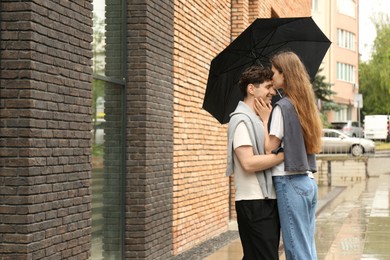 Photo of International dating. Lovely young couple with umbrella spending time together outdoors, space for text