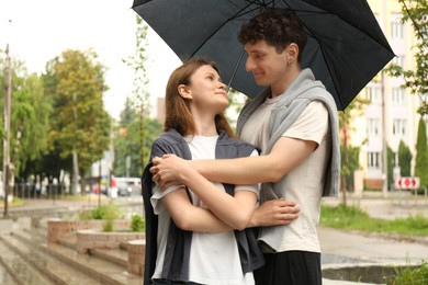 Photo of International dating. Lovely young couple with umbrella spending time together outdoors, space for text