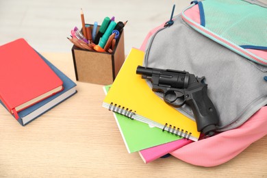 Photo of School stationery and gun on wooden desk, closeup