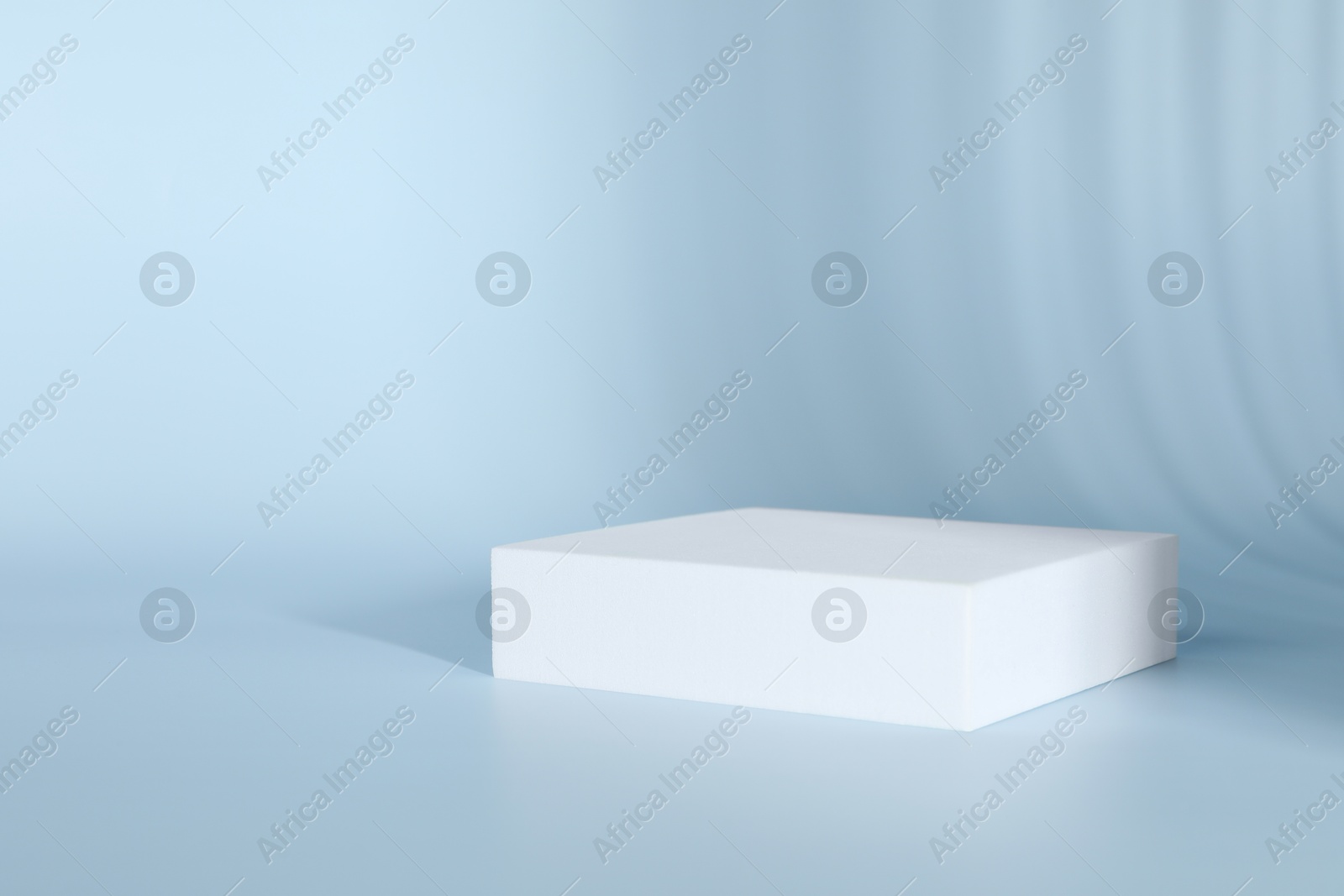 Photo of Presentation of product. White podium on light blue background. Space for text