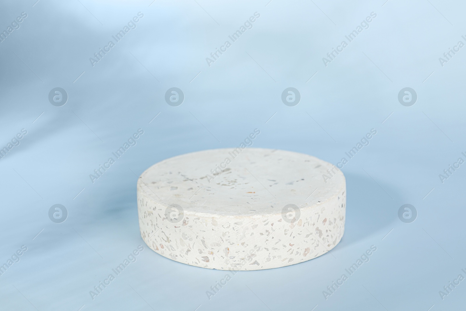 Photo of Presentation of product. Round podium and shadows on light blue background. Space for text
