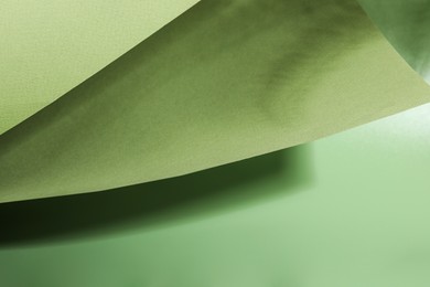 Photo of Presentation of product. Sheets of paper and shadows on green background, closeup