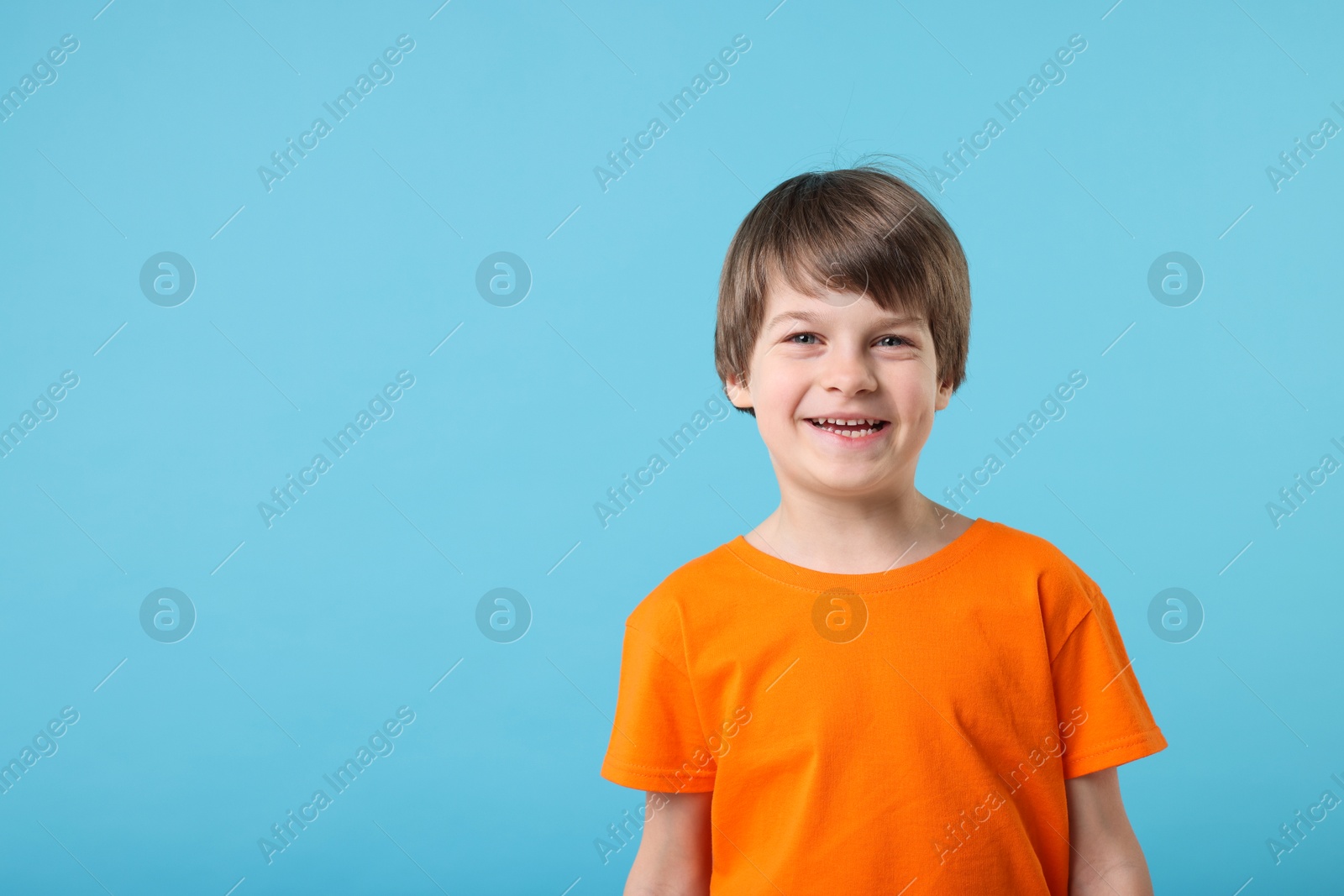 Photo of Portrait of cute little boy on light blue background, space for text