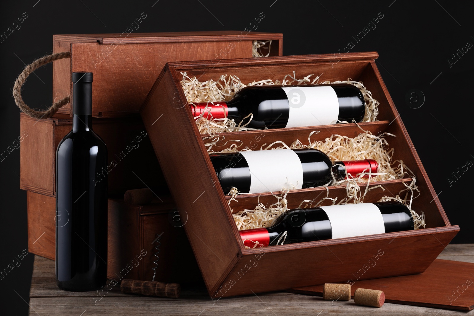 Photo of Box with wine bottles on wooden table against black background