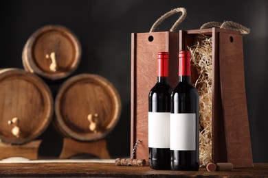 Wooden boxes, corkscrew and wine bottles on table against dark background. Space for text