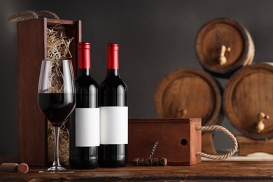 Wooden boxes, corkscrew and wine bottles on table against dark background. Space for text