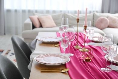 Photo of Beautiful table setting with candles and pink accent in dining room