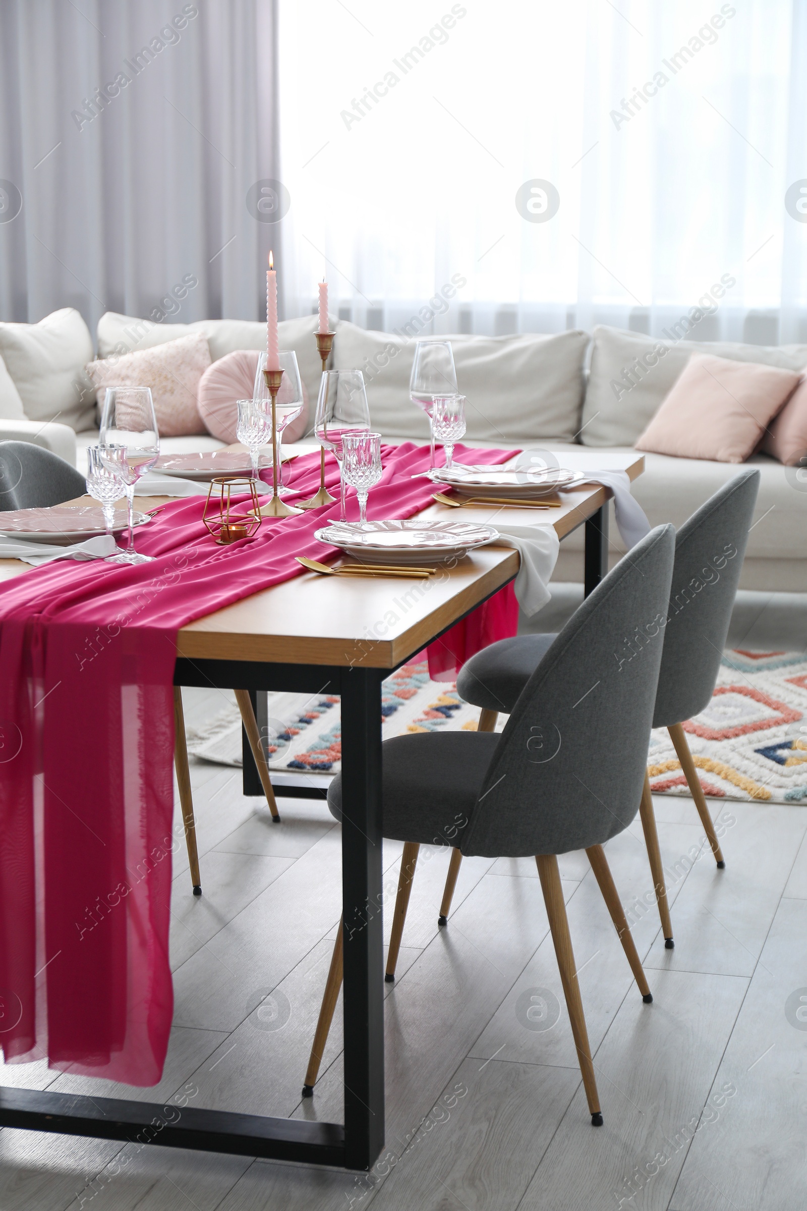 Photo of Beautiful table setting with burning candles and pink accent in dining room