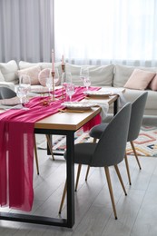 Beautiful table setting with burning candles and pink accent in dining room