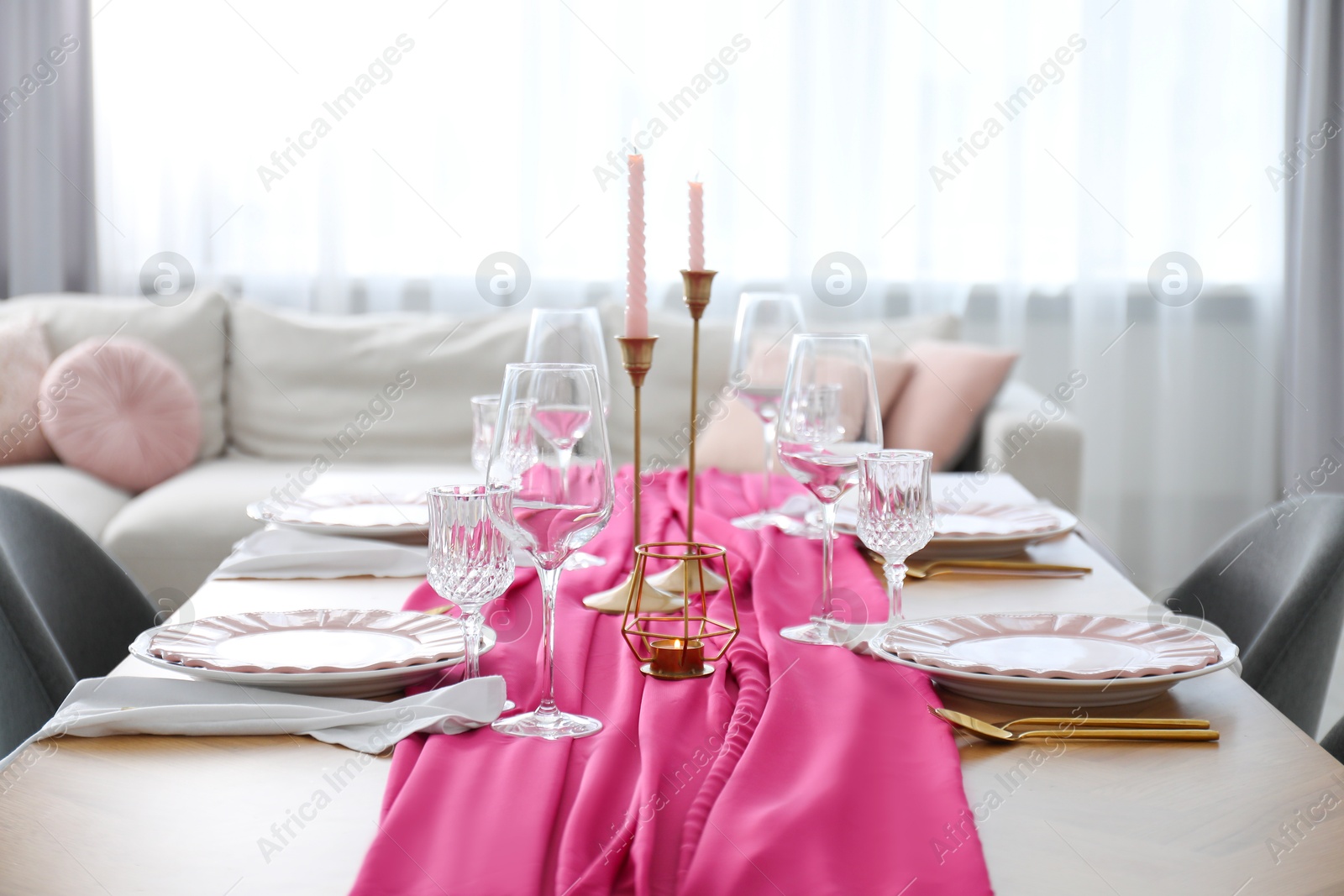 Photo of Beautiful table setting with burning candles and pink accent in dining room