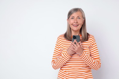 Photo of Senior woman with phone on light grey background, space for text