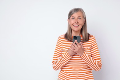 Senior woman with phone on light grey background, space for text