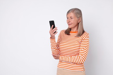 Photo of Senior woman with phone on light grey background, space for text