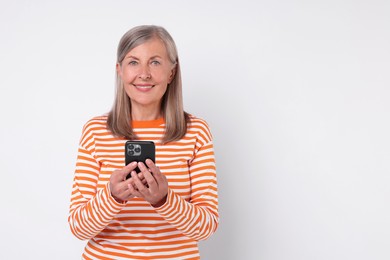 Photo of Senior woman with phone on light grey background, space for text