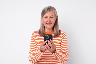 Senior woman with phone on light grey background