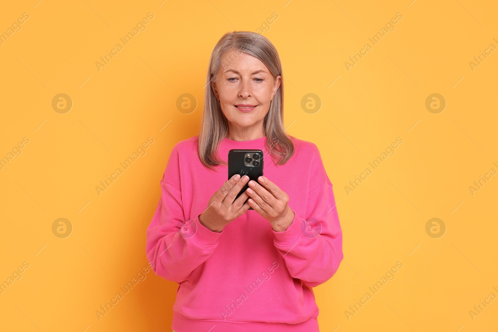 Photo of Senior woman with phone on orange background