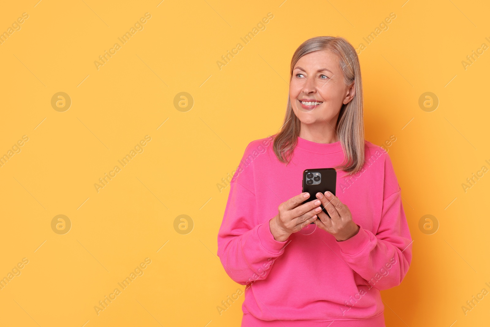 Photo of Senior woman with phone on orange background, space for text