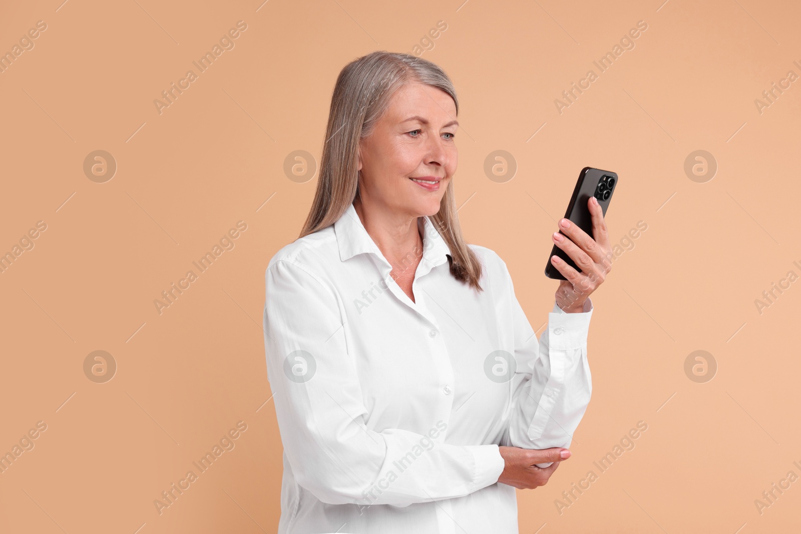 Photo of Senior woman with phone on beige background