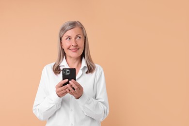 Photo of Senior woman with phone on beige background, space for text