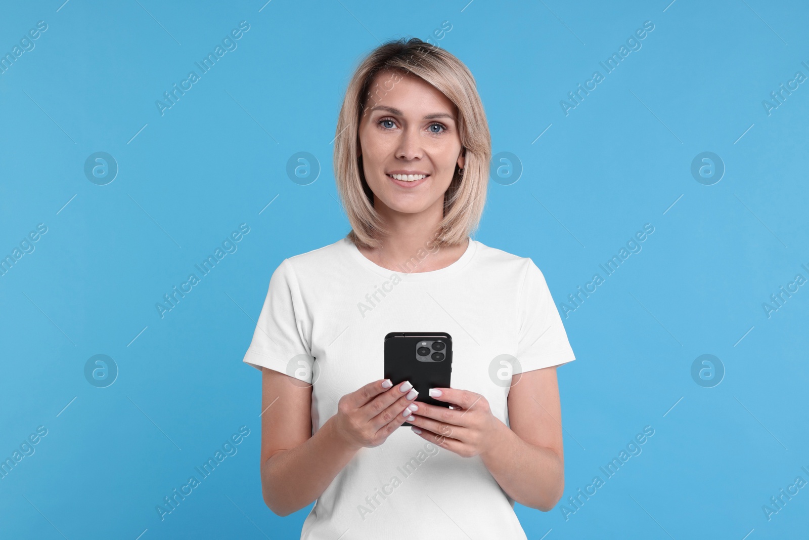 Photo of Happy woman with phone on light blue background