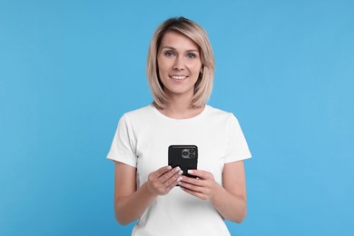 Happy woman with phone on light blue background