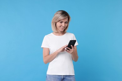 Photo of Happy woman with phone on light blue background