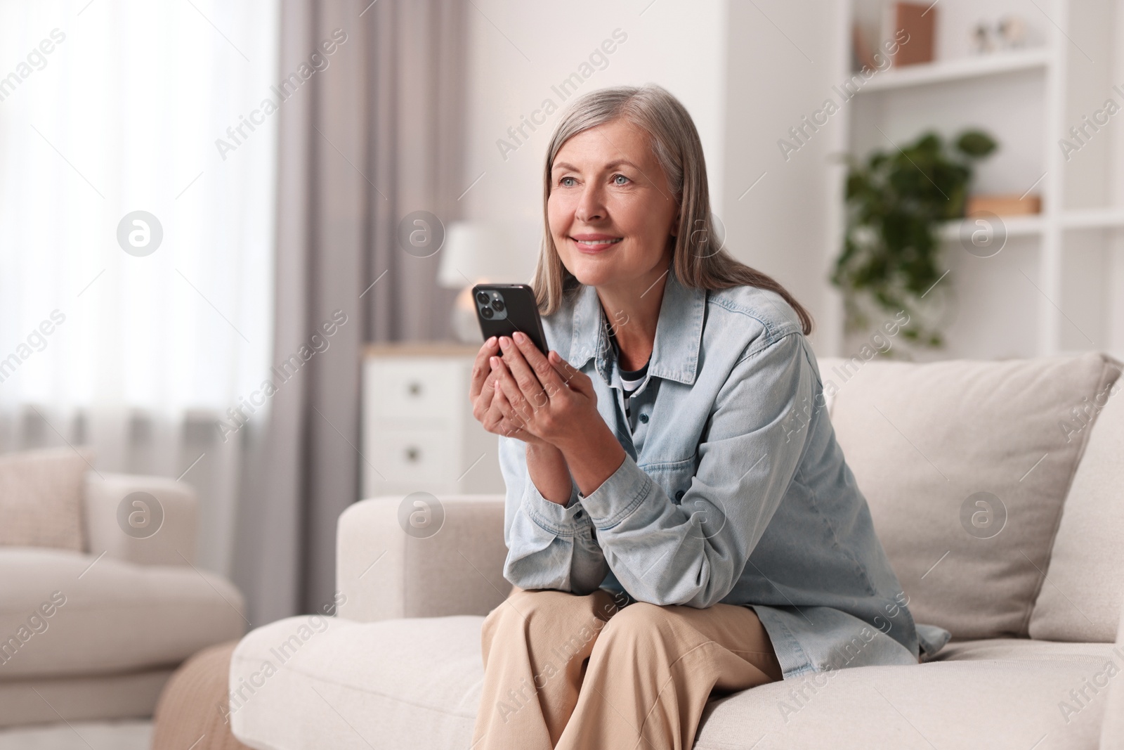 Photo of Senior woman using mobile phone at home