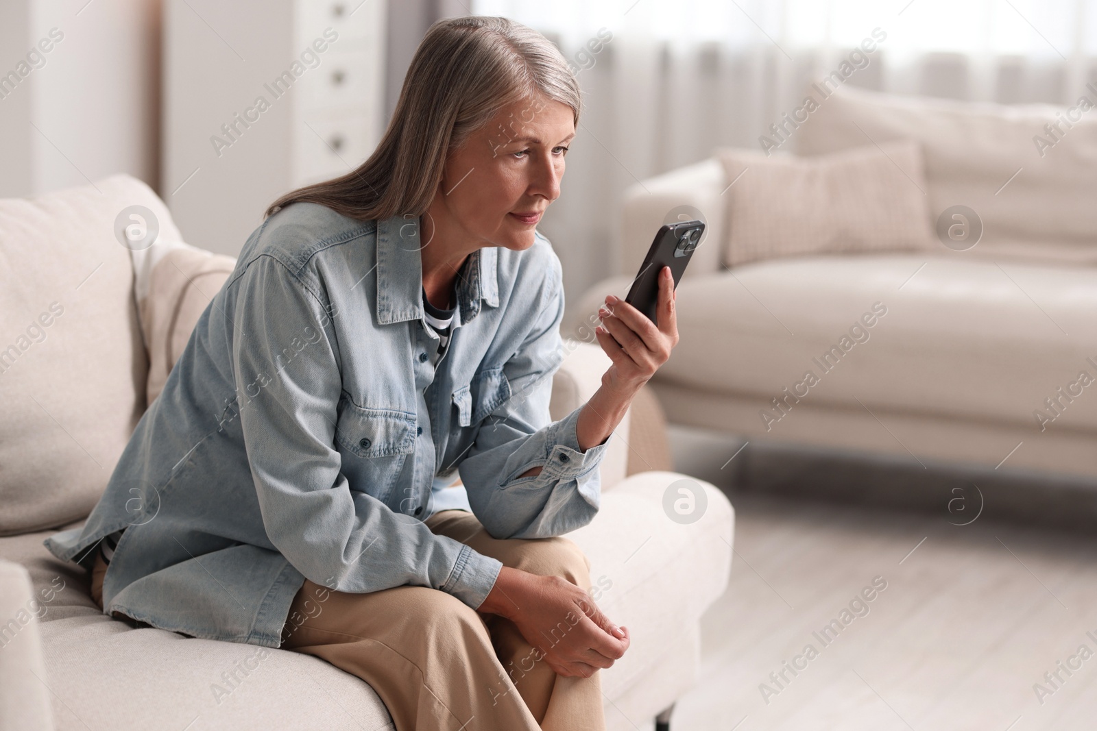 Photo of Senior woman using mobile phone at home, space for text