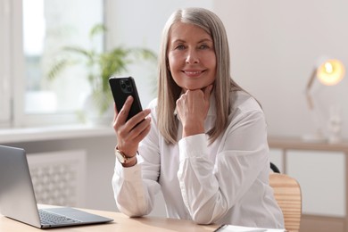 Photo of Senior woman using mobile phone at home