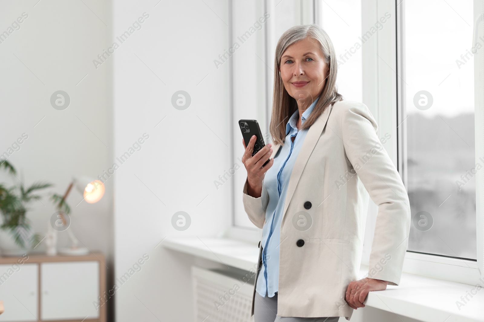 Photo of Senior woman using mobile phone at home, space for text