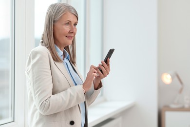 Photo of Senior woman using mobile phone at home