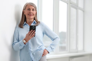 Photo of Senior woman using mobile phone at home, space for text