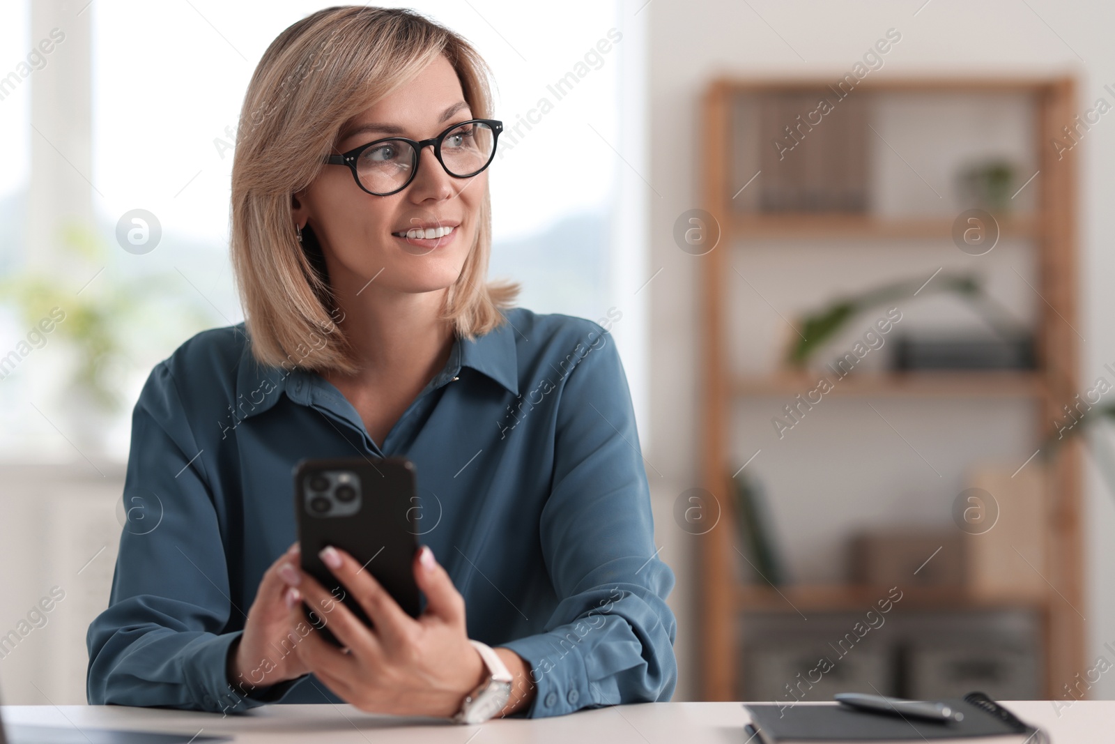 Photo of Happy woman using mobile phone at white table indoors, space for text