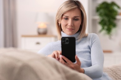 Woman using mobile phone on sofa at home