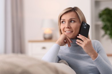 Photo of Happy woman talking on phone at home, space for text