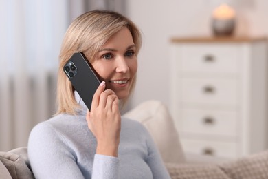 Photo of Happy woman talking on phone at home, space for text