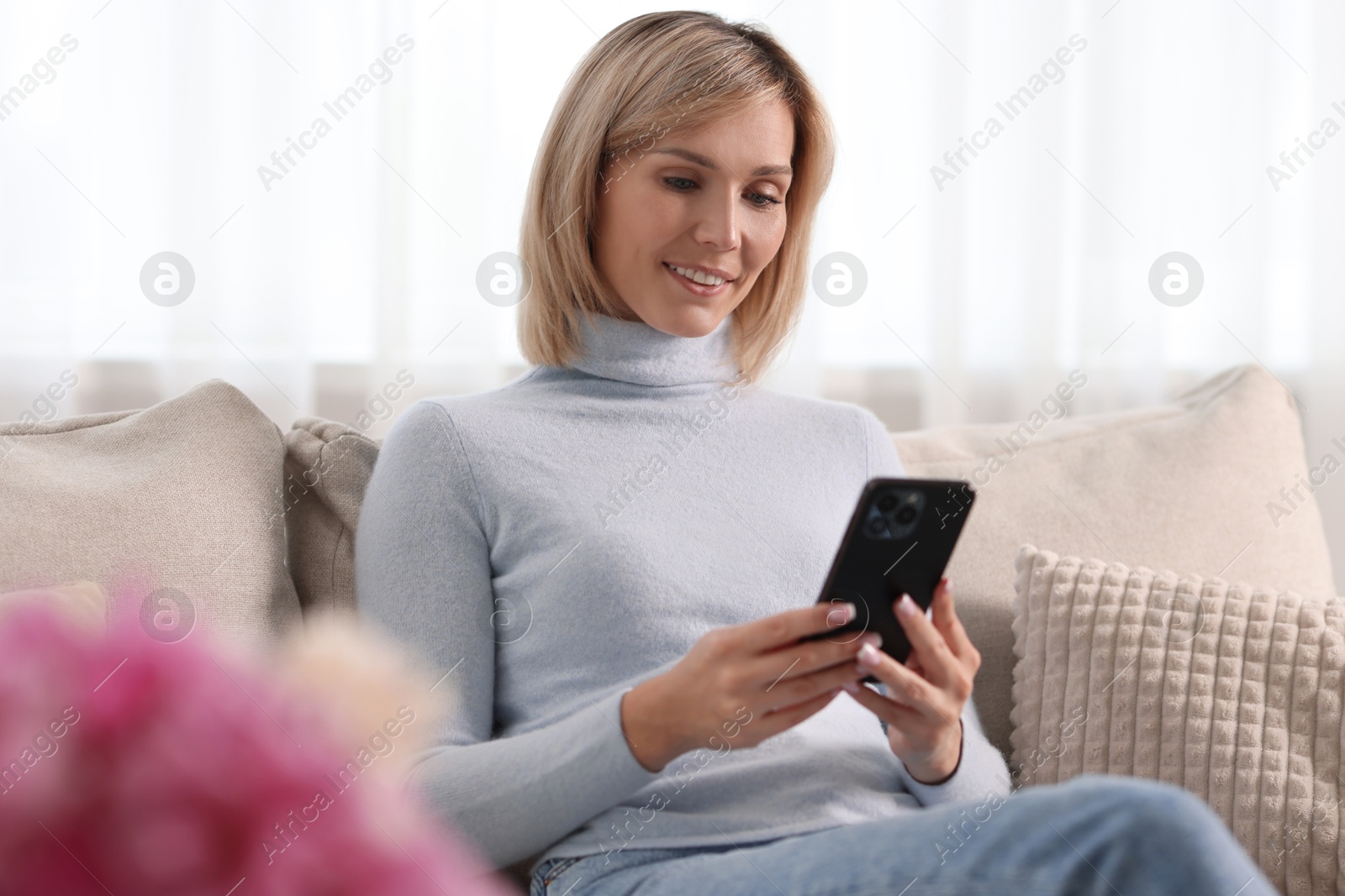 Photo of Happy woman using mobile phone at home