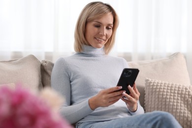 Happy woman using mobile phone at home