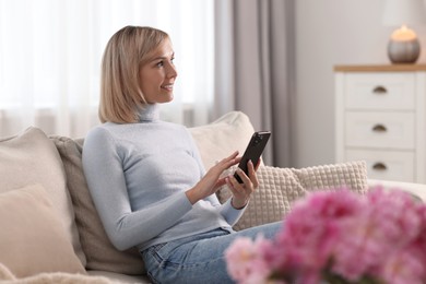 Happy woman using mobile phone at home