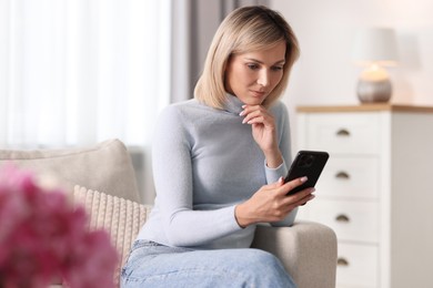 Woman using mobile phone on sofa at home