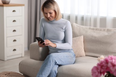 Happy woman using mobile phone at home