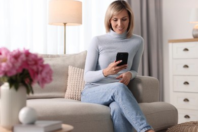 Happy woman using mobile phone at home