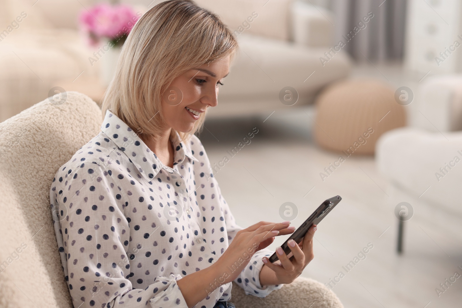 Photo of Happy woman using mobile phone at home, space for text