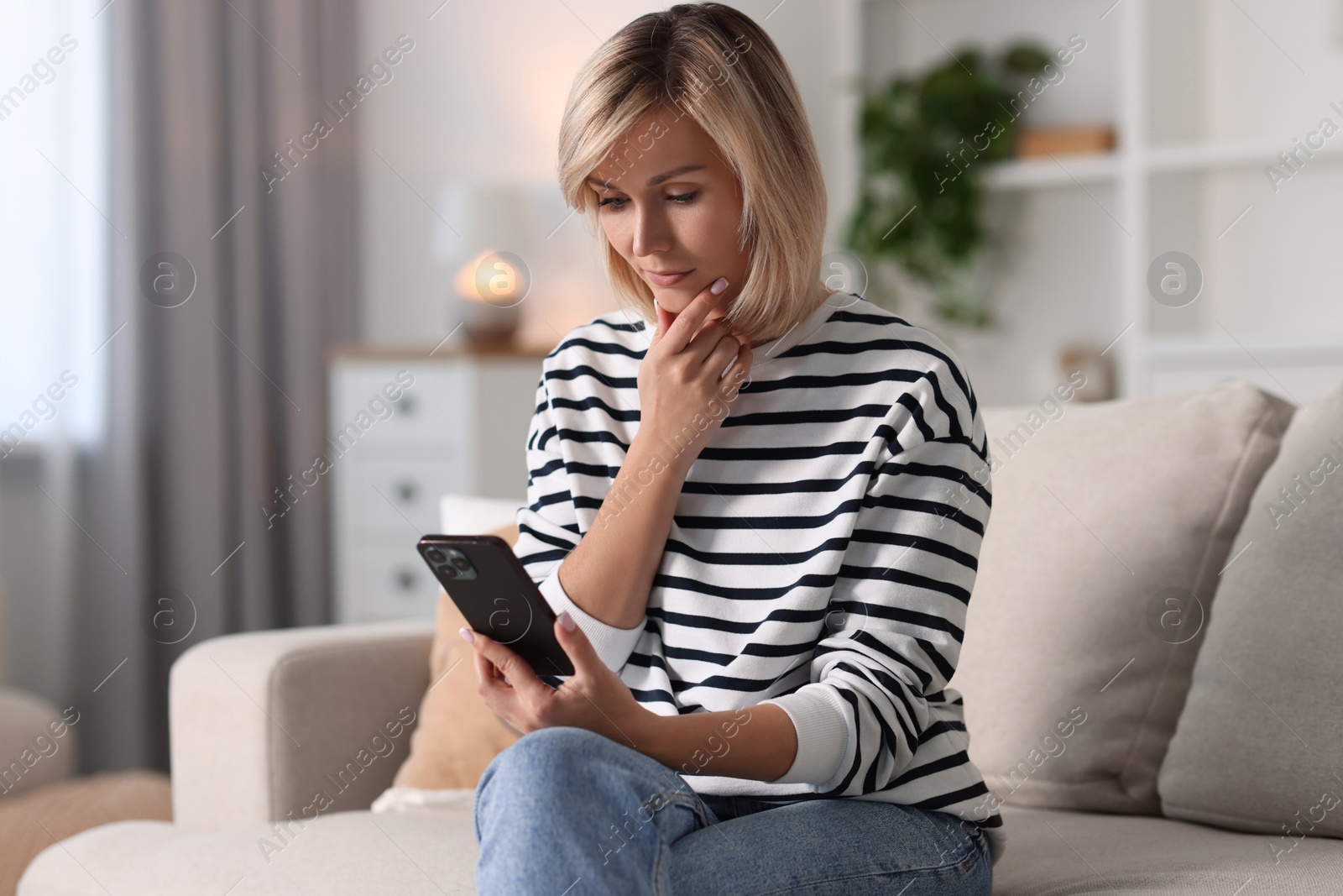 Photo of Woman using mobile phone on sofa at home