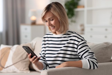 Happy woman using mobile phone at home