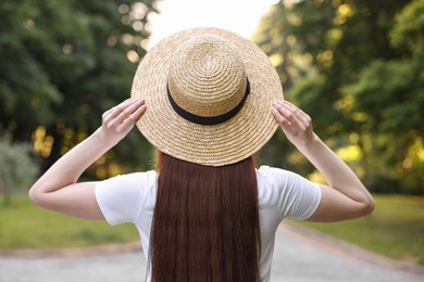 Photo of Woman wearing straw hat outdoors, back view. Spring vibes