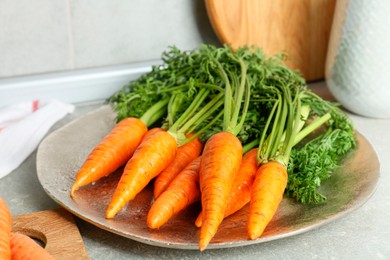 Photo of Tasty ripe juicy carrots on gray textured table, closeup