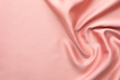 Photo of Crumpled pink silk fabric as background, top view. Space for text