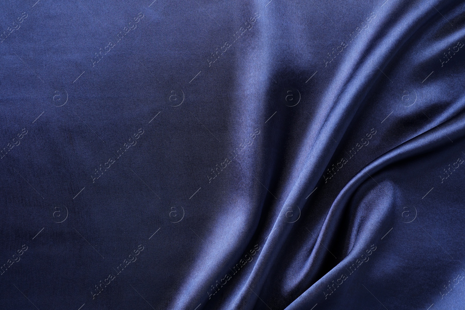 Photo of Crumpled dark blue silk fabric as background, top view. Space for text